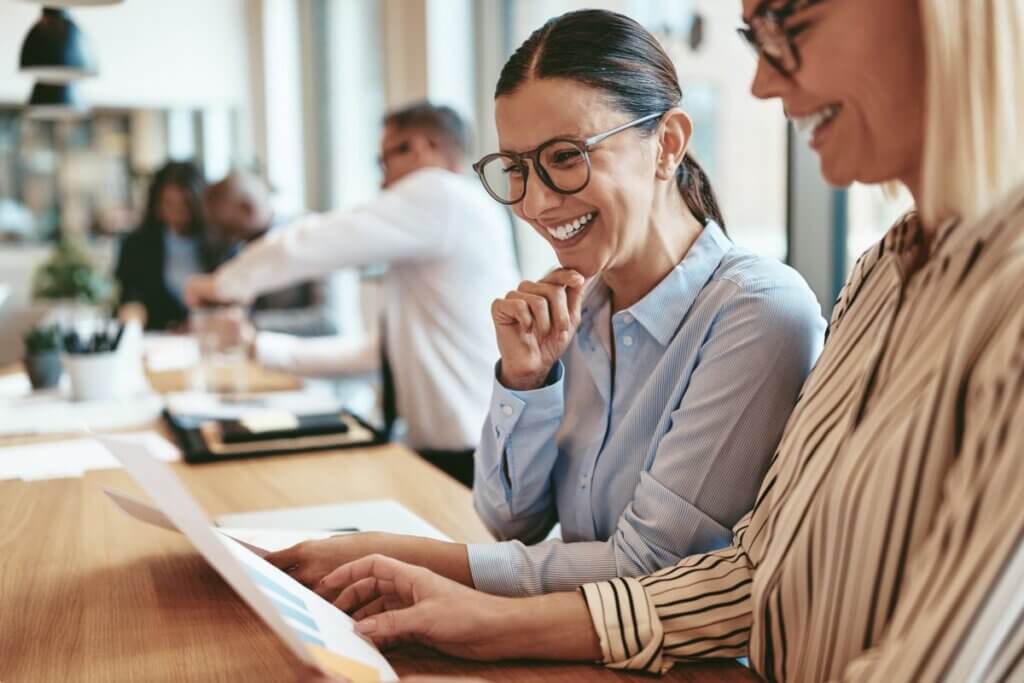 Smiling Businesswomen Going Over Paperwork Together
